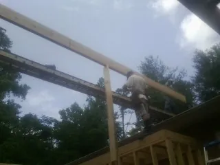 Carpenter setting a ridge beam over a new addition frame — Ice Dam Removal by Roofing Brothers in Ashland